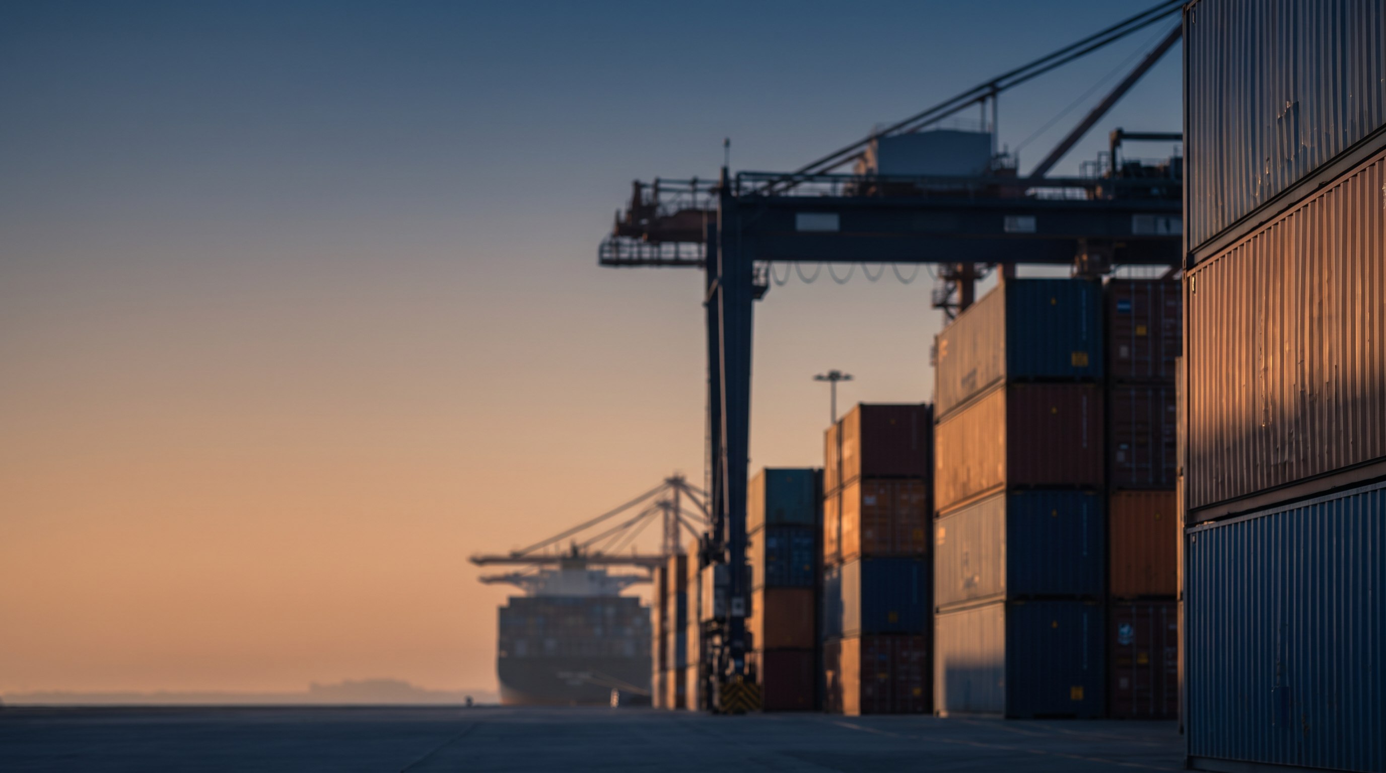 Shipping containers and a cargo crane at a port at golden hour, representing global e-commerce sourcing and logistics